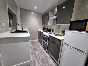 una cocina con electrodomésticos de acero inoxidable y armarios blancos en Manchester St by Prestige Properties SA en Barrow in Furness