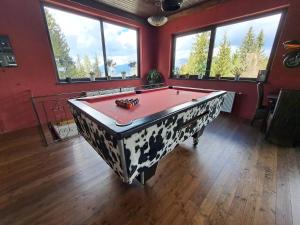 a room with a pool table in a room with windows at Blue Mountain Hotel in Afritz