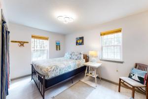 a bedroom with a bed and a desk and two windows at Main Deck in Pacific City