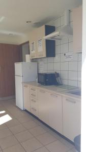 a kitchen with white cabinets and a refrigerator at Wille Amber in Mielno