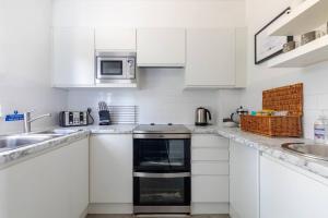 a white kitchen with a stove and a sink at Toppesfield Vineyard luxury, contemporary villa - 2 adults in Toppesfield