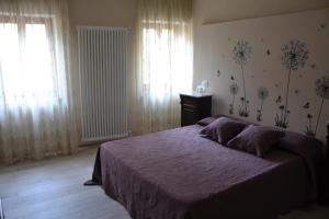 a bedroom with a bed with purple sheets and windows at Il nido dei Priori in Volterra