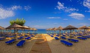 a bunch of chairs and umbrellas on a beach at Tom's House in Nea Karvali