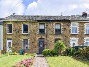 a brick house with a black door at Cwmcarn Cottage in Crosskeys