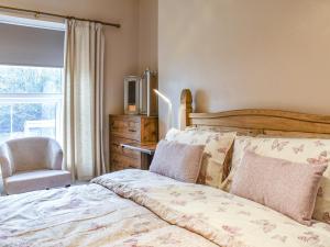 a bedroom with a bed and a chair and a window at Cwmcarn Cottage in Crosskeys