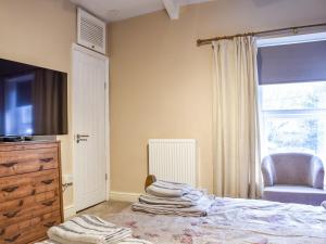 een slaapkamer met een bed, een televisie en een stoel bij Cwmcarn Cottage in Crosskeys