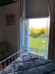 a bedroom with a large window with a view of a yard at Maison gasconne in Castillon-Debats