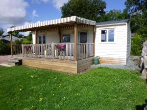 a tiny house with a porch and a deck at Mobil-home Camping 3 étoiles in Genouillé +7 photos