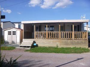 ein kleines Haus mit einer Veranda und einer Terrasse in der Unterkunft Mobil-home Camping 3 étoiles in Genouillé