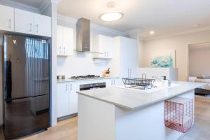 uma cozinha com armários brancos e um frigorífico preto em Modern Town house - Close to CBD em Perth