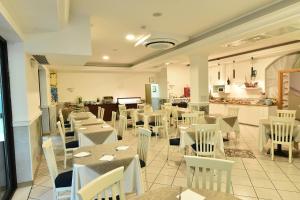 a restaurant with white tables and white chairs at Hotel Okinawa in Rimini