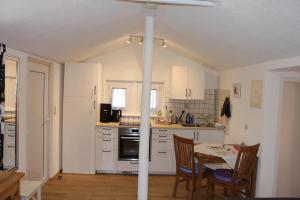 Una cocina con gabinetes blancos y una mesa con sillas. en Ferienhaus Franzl, en Schwangau