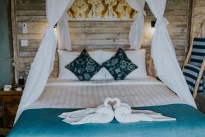 2 asciugamani cigni su un letto in una camera da letto di Lanussa Hill Villa a Nusa Lembongan