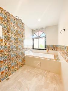 een badkamer met een bad en een raam en tegels bij La Reina Maroc Hotel ปากช่อง เขาใหญ่ in Pak Chong