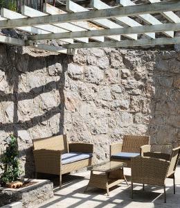 three chairs and a table on a patio with a stone wall at Casa Bella in Karlobag