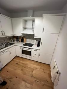 a kitchen with white cabinets and a wooden floor at Art & View - Apartment in Bad Gastein