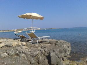 a table and chair with an umbrella on the beach at Vista Azzurra in Marina di Modica