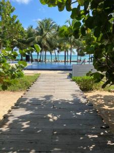 a pathway leading to a beach with trees and a pool at Sandy Shores in Trincomalee