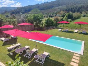 een zwembad met stoelen en rode parasols in een tuin bij Sotam Country House EN342 in Góis