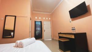 a bedroom with a bed and a mirror and a television at Penginapan Malompek Syariah in Duku