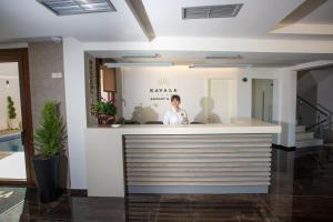 a woman standing behind a counter in a building at Kavala Resort & Spa in Néa Karváli