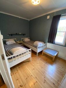 een slaapkamer met 2 bedden en een houten vloer bij Cabin 70m from lake. Big garden in Östersund