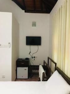 a bedroom with a bed and a tv on the wall at Langama Thena - ළඟම තැන in Anuradhapura