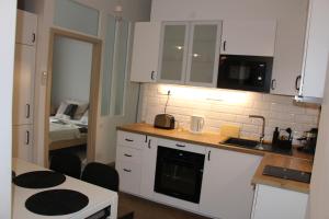 cocina con armarios blancos y encimera en Larix apartman en Budapest
