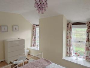 a bedroom with a bed and a window and a chandelier at Delfryn in Pen-y-groes