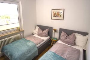 two beds in a small room with a window at Ferienwohnung mit herrlichem Ausblick meerwärts in Wilhelmshaven
