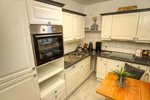 a kitchen with white cabinets and a wooden table at Ferienwohnung mit herrlichem Ausblick meerwärts in Wilhelmshaven