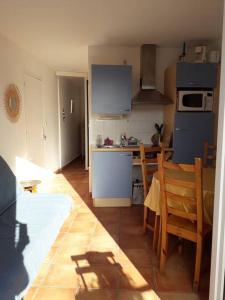 a kitchen with a table and a kitchen with blue appliances at Banyuls La Grande Bleue : studio T1 in Banyuls-sur-Mer