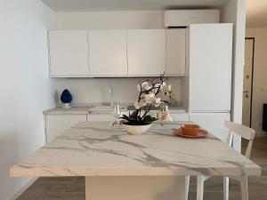 a kitchen with a marble table and white cabinets at BOUTIQUE HOME LIGNANO in Lignano Sabbiadoro