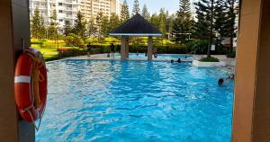 a large swimming pool with people in the water at Tagaytay Family Staycation Spacious 2 Unit Condo Sleeps 5 to 7 in Tagaytay