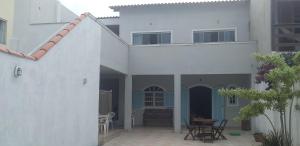 Casa blanca con patio y mesa en Aluguel Temporada CABO FRIO, en Cabo Frío