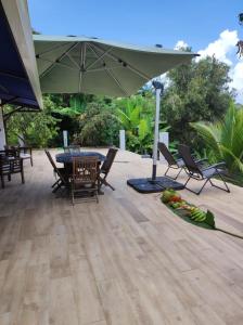 eine Terrasse mit einem Tisch, Stühlen und einem Sonnenschirm in der Unterkunft L'Eucalyptus in La Trinité