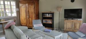 a living room with a couch and chairs and a tv at La Petite Maison in Givry