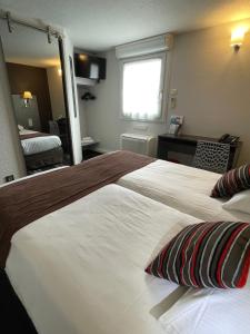 a hotel room with a large bed and a mirror at Kyriad Direct Limoges Nord in Limoges