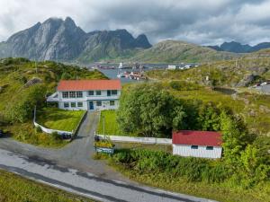 a house on a hill with mountains in the background at Sundet Lofoten Holiday House in Sund