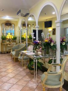 uma sala de espera com mesas, cadeiras e flores em Sourire Hotel em Roma