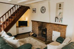 a living room with a fireplace and a clock on the wall at CLIFFE COTTAGE - Countryside Cottage in Castleton, Peak District National Park in Castleton