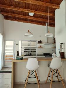 two white bar stools in a kitchen with wooden ceilings at Quinta El Hornero in Esperanza