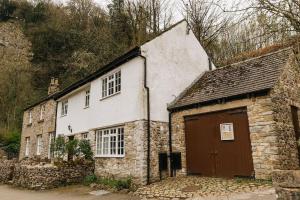an old stone building with a brown door at CLIFFE COTTAGE - Countryside Cottage in Castleton, Peak District National Park in Castleton