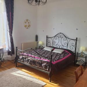 ein Schlafzimmer mit einem schwarzen Bett und einer lila Decke in der Unterkunft VILLA DE SOUZA in Bouillé-Loretz