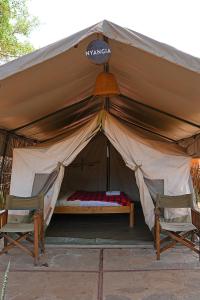 a tent with two chairs and a bed in it at Kara-Tunga Safari Camp in Moroto