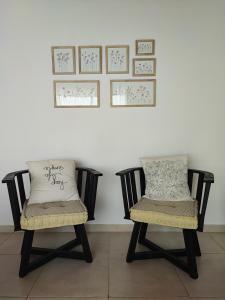 duas cadeiras sentadas em frente a uma parede branca com quadros em Quinta El Hornero em Esperanza