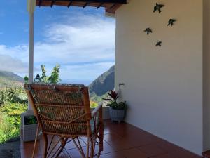 une terrasse couverte avec un fauteuil à bascule et des oiseaux sur le mur dans l'établissement Terra Batista house, à Porto da Cruz