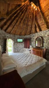 Windmill Shkodra Gesthouse Camping & Grill في شكودر: غرفة نوم بسرير كبير في مبنى حجري