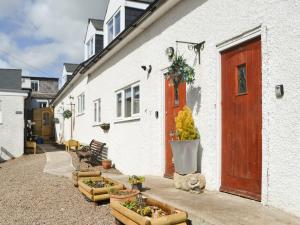 a white building with a red door and some plants at Cygnet Cottage - Uk43546 in Belford