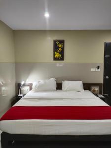 a bedroom with a large bed with a red blanket at Kottavathil Hotel in Tripunnittara